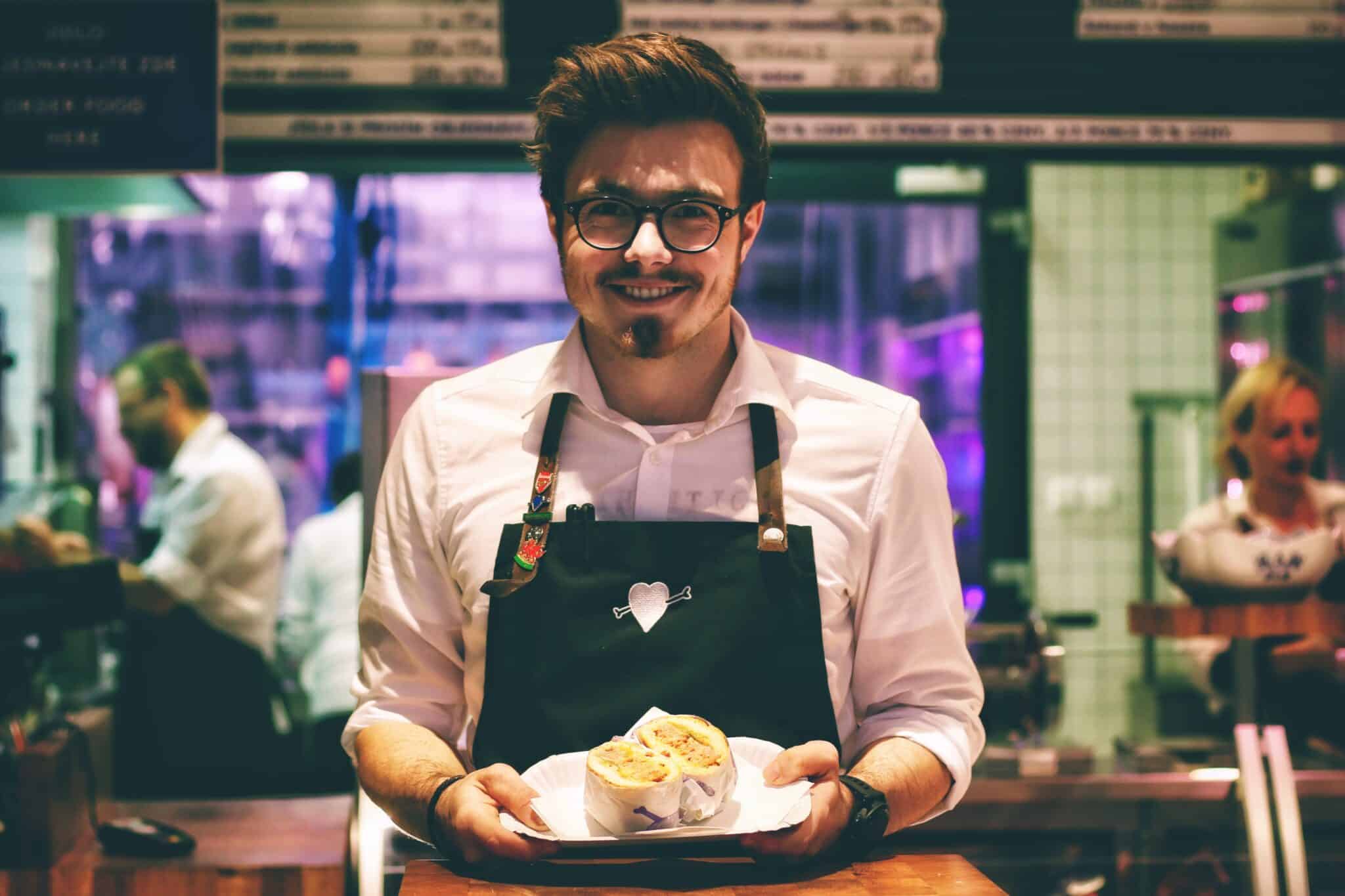A smiling waiter serving a sandwich